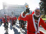 People dressed in Santa Claus costumes ride on bicycles through the streets of Rome