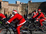 People dressed in Santa Claus costumes ride on bicycles through the streets of Rome