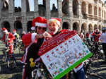 People dressed in Santa Claus costumes ride on bicycles through the streets of Rome