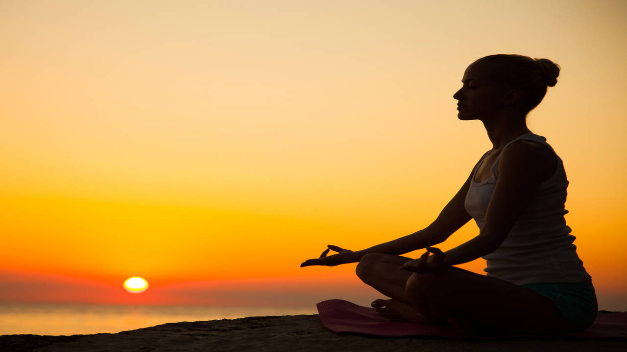 Close-up of a woman performing yoga postures at sunset sitting on