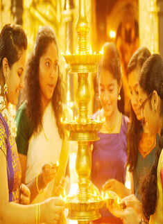 Girls dressed in traditional attire light the lamps