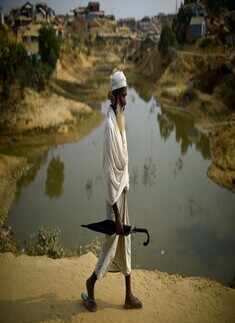 A Rohingya refugee walks with an umbrella at Jamtoli refugee camp in Cox's Bazaar